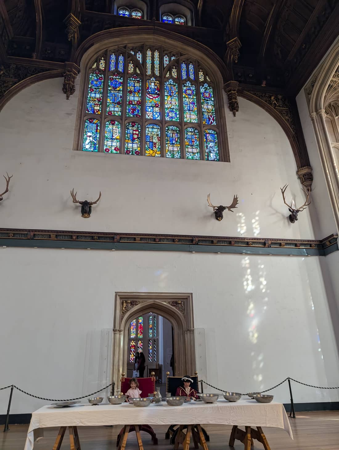A grand medieval hall with stained-glass windows and banquet tables